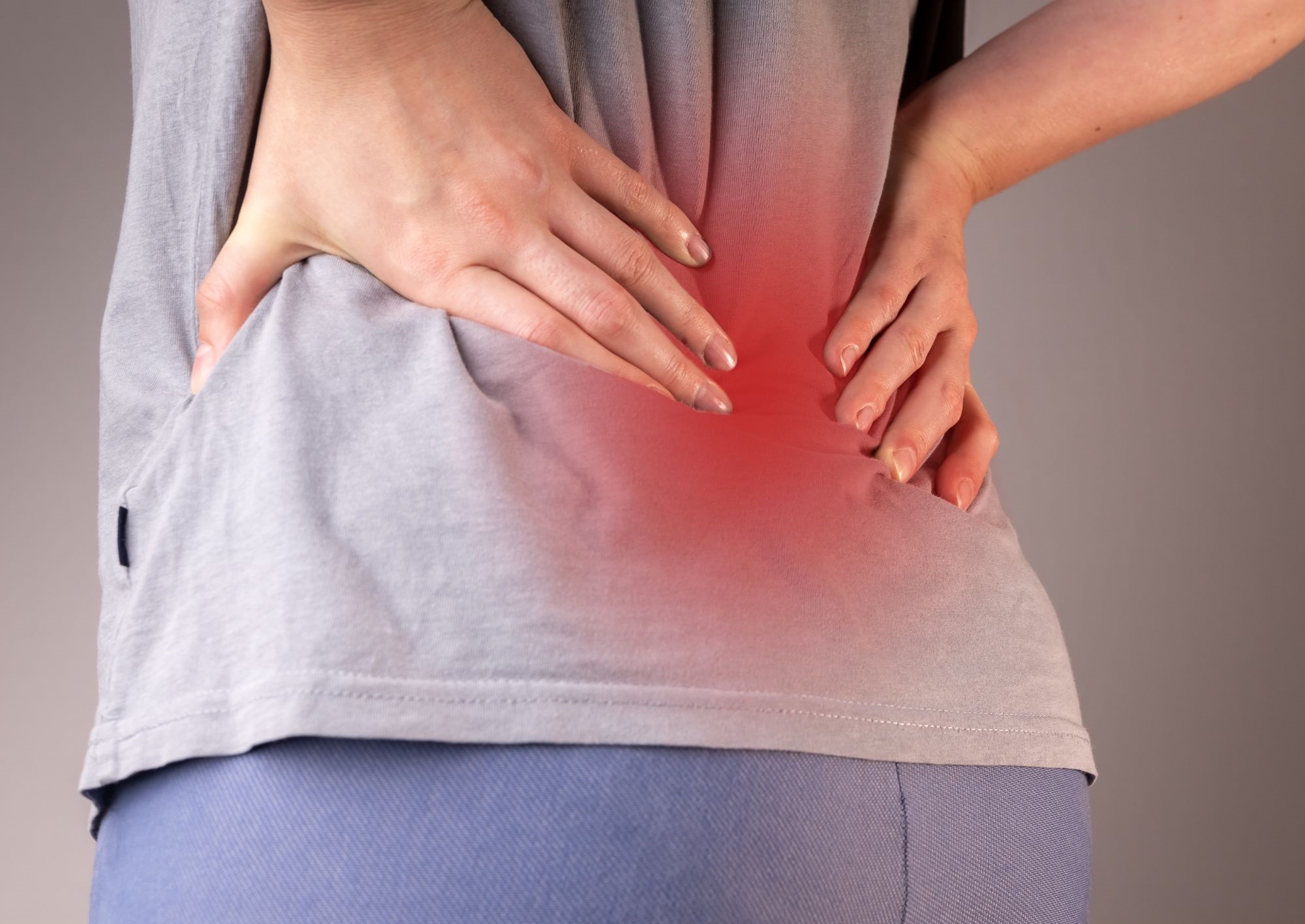 a woman holding her back with pain from sciatica who has went to see the back pain experts in lake country